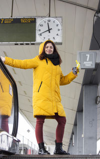 Young woman in yellow hood jacket at the train station