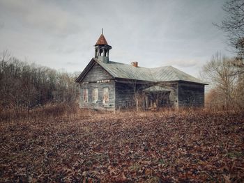 Old school building on field against sky