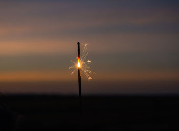 Close-up of fireworks on field against sky during sunset