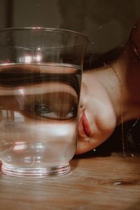 Cropped hand of woman drinking glass on table