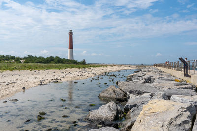 Lighthouse by sea against sky