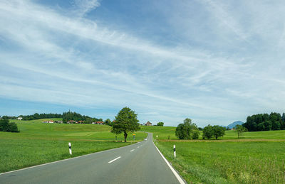 Road amidst field against sky