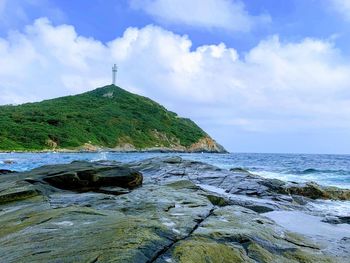 Scenic view of rocks by sea against sky