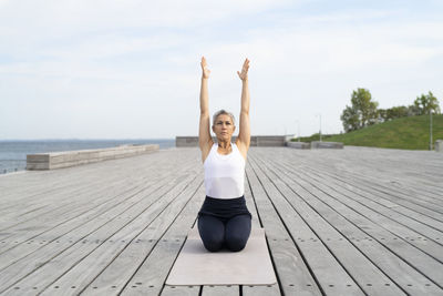 Woman practicing yoga on pier