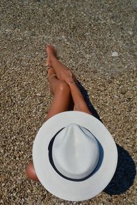 Woman wearing hat while relaxing on sand at beach