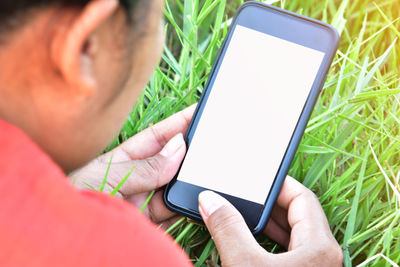 Cropped image of woman using phone on field