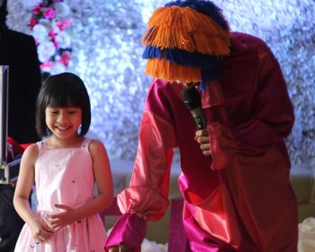 Smiling girl standing by clown on stage