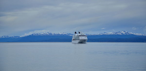 Scenic view of sea by snowcapped mountains against sky