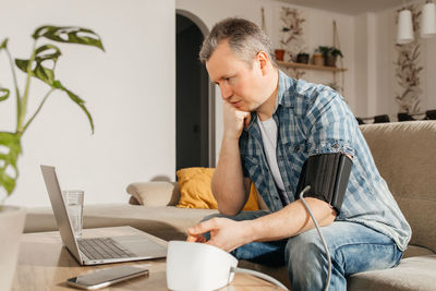 Side view of young man using laptop at home