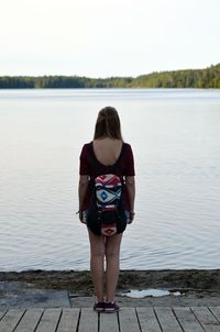 Rear view of woman standing in lake against clear sky