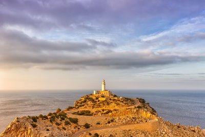 Lighthouse amidst sea and buildings against sky