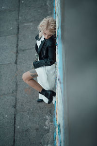 Woman looking away while standing against wall