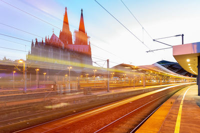 Light trails on railroad station in city against sky