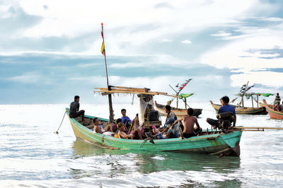 People on boat in sea against sky