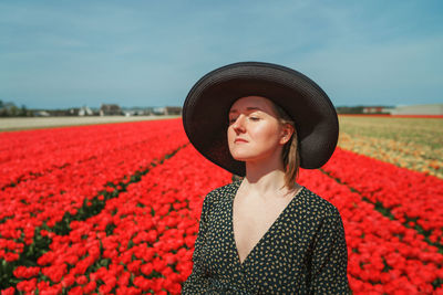 Mid adult woman wearing hat standing against red wall