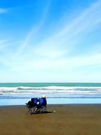 Chairs on beach against blue sky