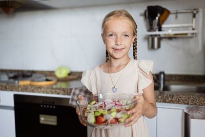 Portrait of smiling young woman holding ice cream at home