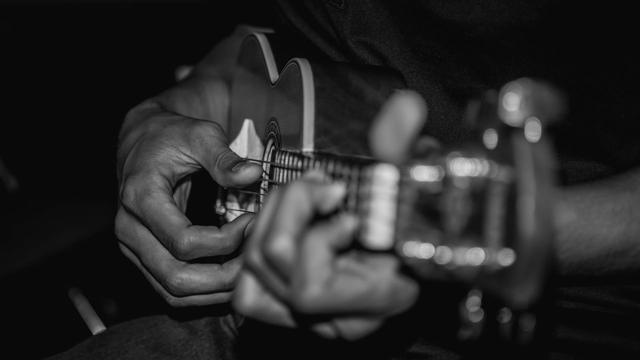 MIDSECTION OF MAN PLAYING GUITAR AT CONCERT