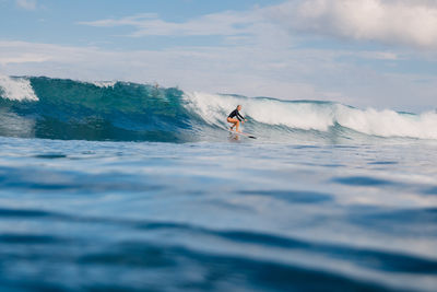 Rear view of man surfing in sea against sky