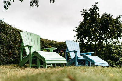 Empty chairs on field against sky