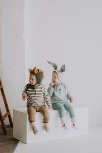 Rear view of friends sitting against white wall