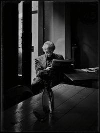 Man reading newspaper while sitting on table at home 