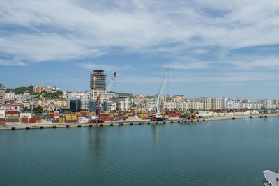 Sea by buildings against sky in city