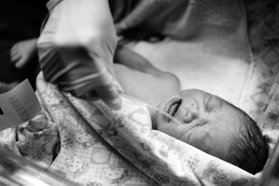 Cropped hand of doctor holding pipe on baby boy crying at hospital