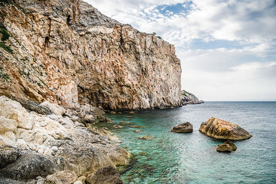 Rock formation in sea against sky