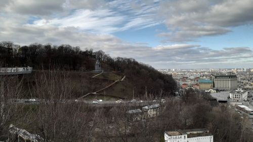 Trees and buildings in city against sky