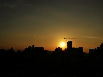 Silhouette buildings against sky during sunset