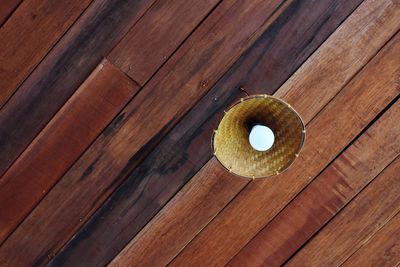 Low angle view of light bulb hanging from wooden ceiling