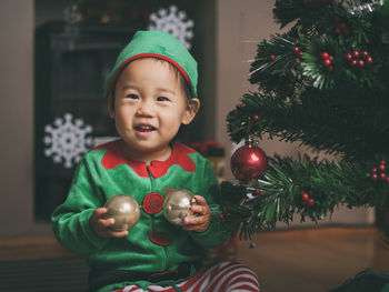 Cute baby girl by christmas tree at home