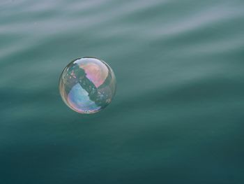 Close-up of soap sud bubble flying over water