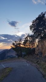 Road amidst trees against sky during sunset