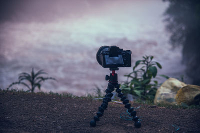 Camera photographing on field by sea against sky