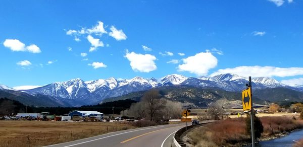 Road by snowcapped mountains against sky