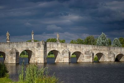 Arch bridge over river against sky