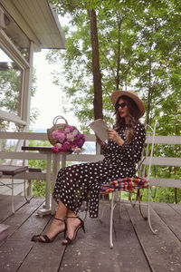 Young woman reading book while sitting at porch