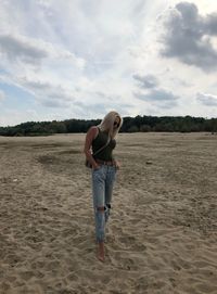 Full length of woman standing on beach against sky