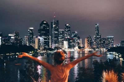 Rear view of woman with illuminated cityscape in background