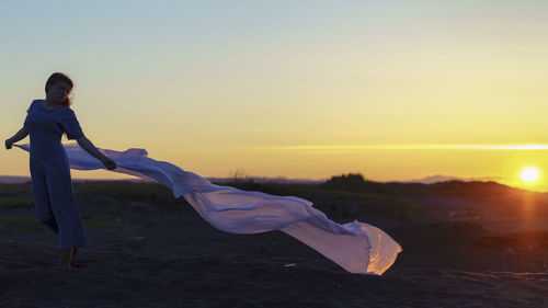 Full length of young woman against sky during sunset