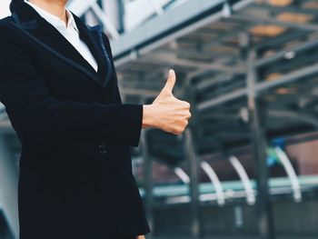 Midsection of businesswoman showing thumbs up