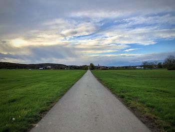 Road amidst field against sky