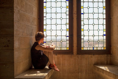 Rear view of man looking through window