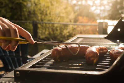 Close-up of hand grilling sausages