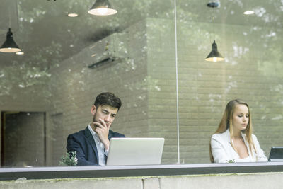 Business colleagues working in office seen through window