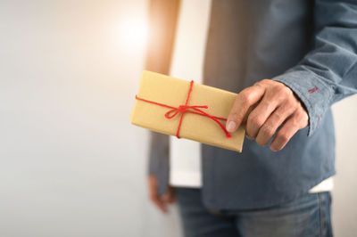 Midsection of man holding paper while standing against wall