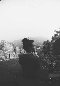 Woman photographing on mountain against clear sky