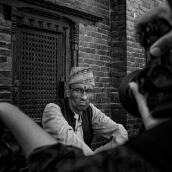 Portrait of man holding camera against wall